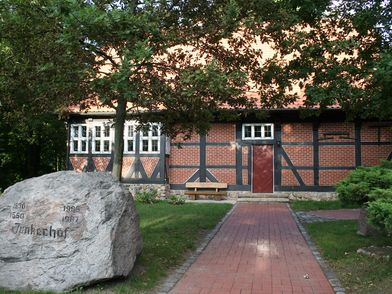 Weg zum Junkerhof Wittingen mit einem großen Stein auf der linken Wegseite. 