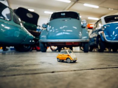 Kleines Modellfahrzeug vor echtem Original