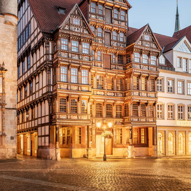 Blick auf das beleuchtete Wedekindhaus und den Renaissance-Erker des Tempelhauses am historischen Marktplatz Hildesheim in der Abenddämmerung