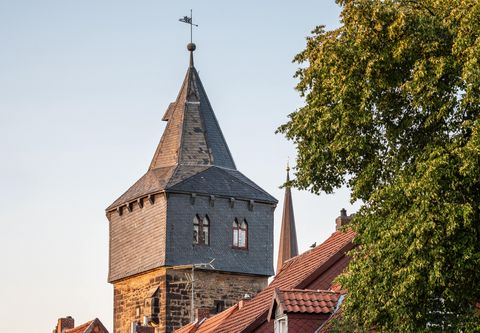 Blick vorbei an einem Baum auf den Kehrwiederturm, über den Dächern von Fachwerkhäusern in der Abenddämmerung