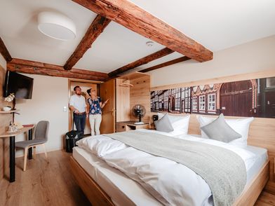 2 Menschen in einem Hotelzimmer im Fachwerkstil.