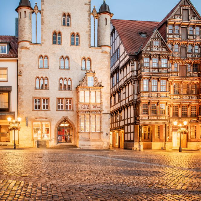 Angestrahltes Tempelhaus mit Renaissance-Erker und Wedekindhaus auf dem historischen Marktplatz Hildesheim in der Abenddämmerung