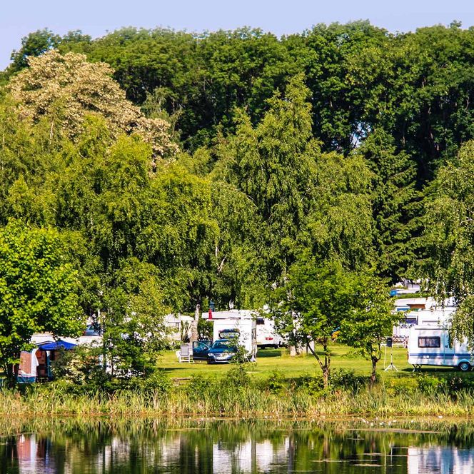 Blick über den See auf das Seecamp Derneburg mit Wohnmobilen