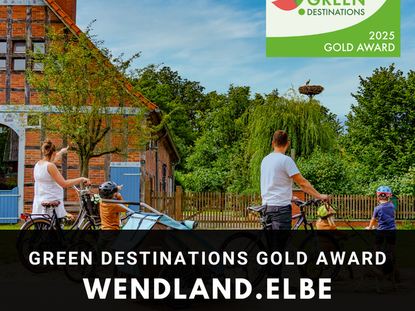 Sommerliches Bild einer Familie im Grünen vor einem Bauernhaus